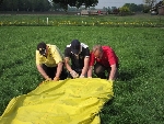 Drei Männer alleine auf dem Feld. Der Ballon wird gerollt.